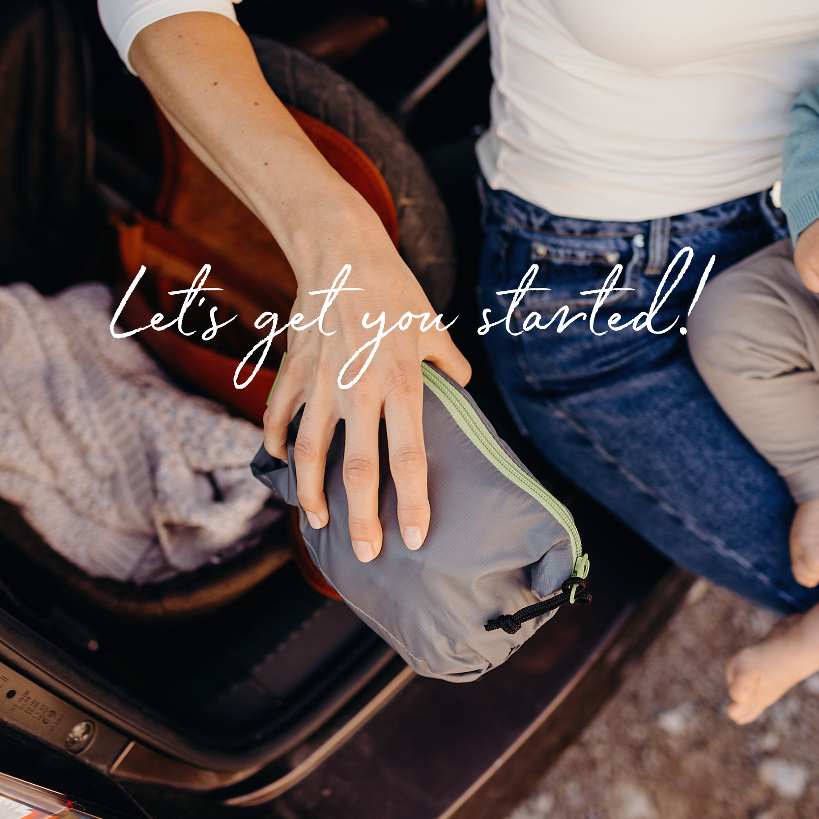 A woman's hand holding a packed boba air carrier while her son sits in her lap next to a stroller.